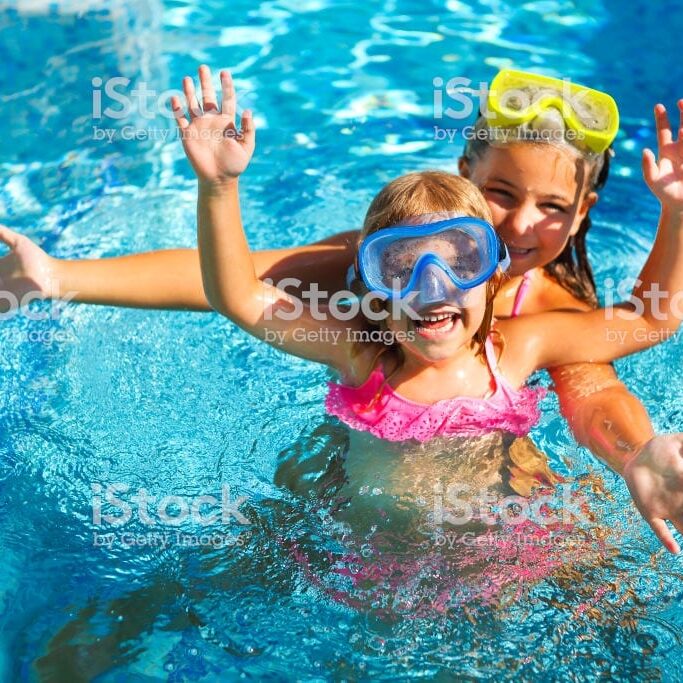 Two funny girls playing in swimming pool. Vacation and travel concept